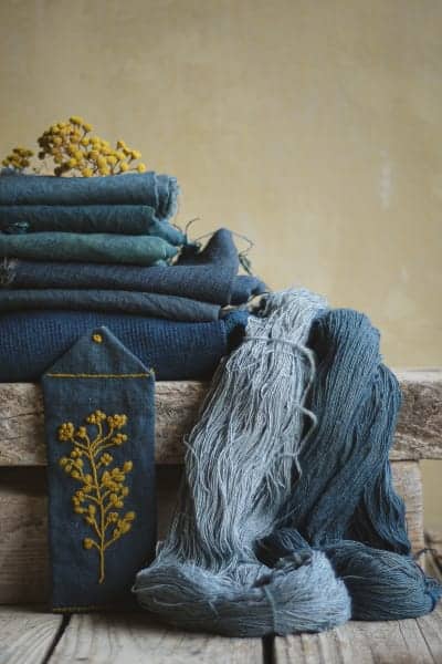 Divers textiles teints à l'indigo : deux écheveaux bleus dont l'un plus clair, du coton et du lin d'un bleu profond.