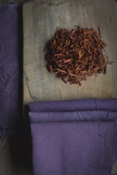 Du bois de campêche sur une planche en bois avec des coupons de lin teints en violet