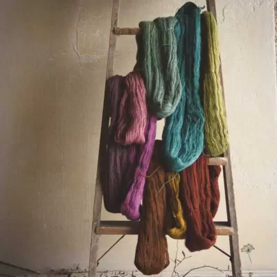 Neufs écheveaux de laine de neufs couleurs différents posés sur un escabeau en bois